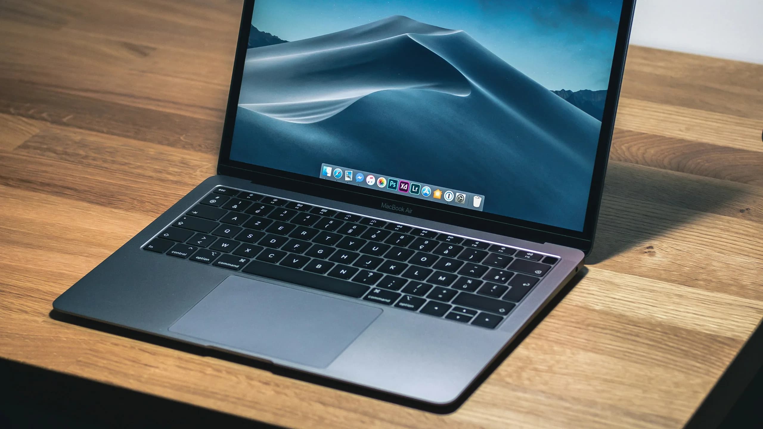A laptop open on a wooden desk, ready to work.
