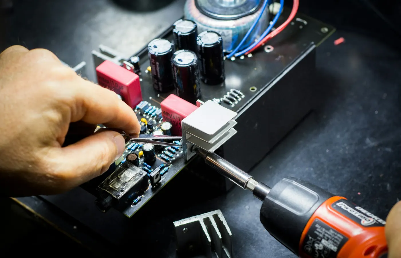 A technician at the bench, soldering on a board.